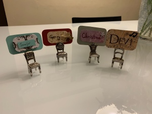 Four tiny silver chairs which all hold a decorate name card
