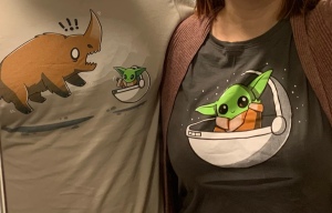 A close up of my partner and I wearing  tshirts with cartoon versions of the child and the mudhorn from the mandalorian 